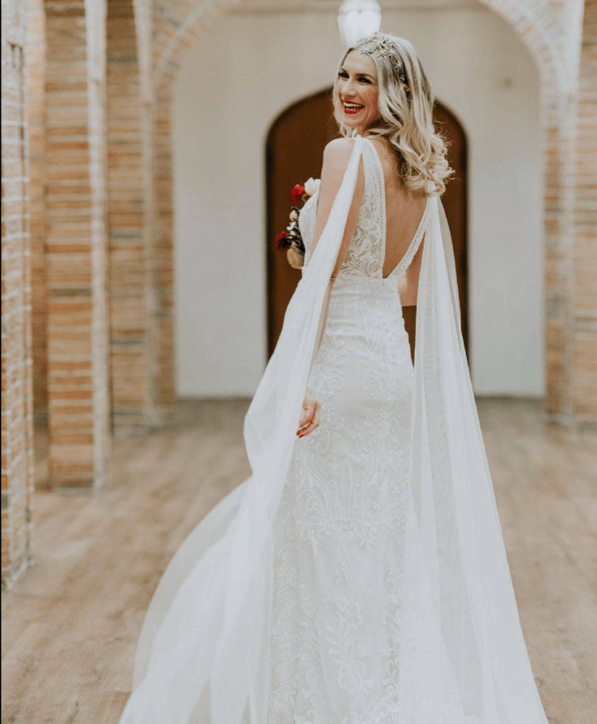 Bride wearing wedding dress with open back and veil on shoulders