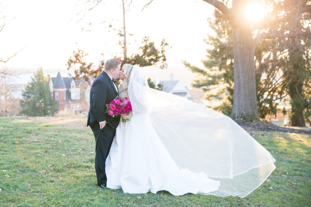 Bride and groom portrait outside with veil flowing